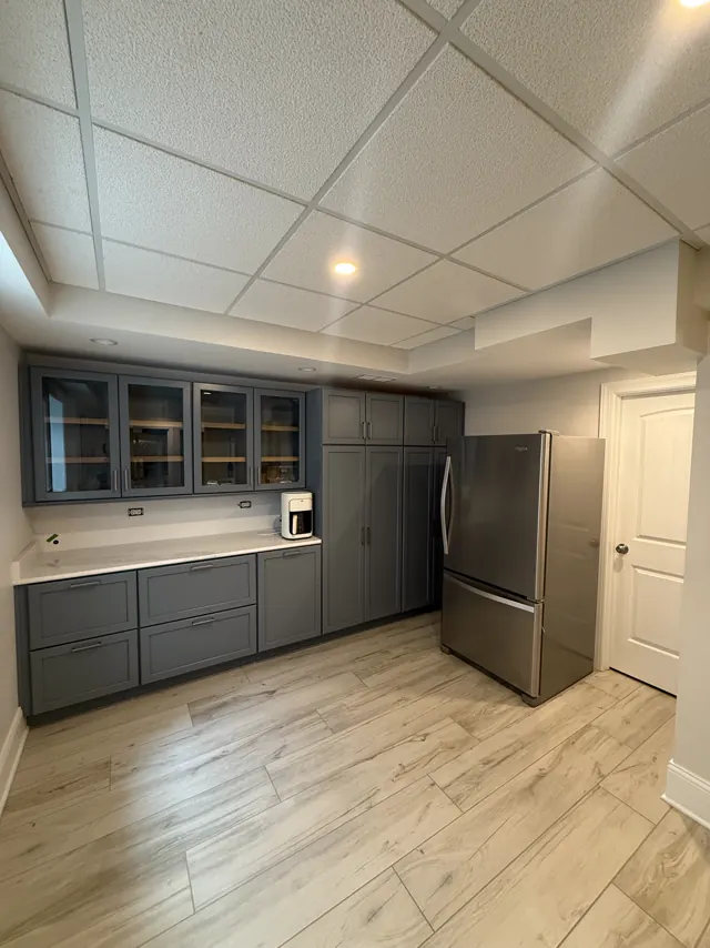 SRC kitchen with gray shaker cabinets, glass-front uppers and a stainless fridge