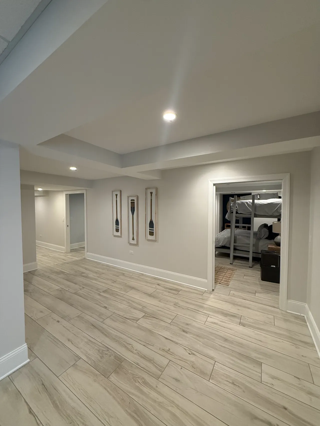 Finished basement hallway with recessed lights leading to a bunk room