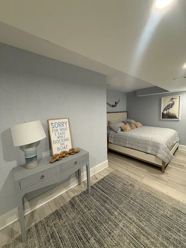 Basement guest bedroom with textured wallcovering and wood-look tile floor