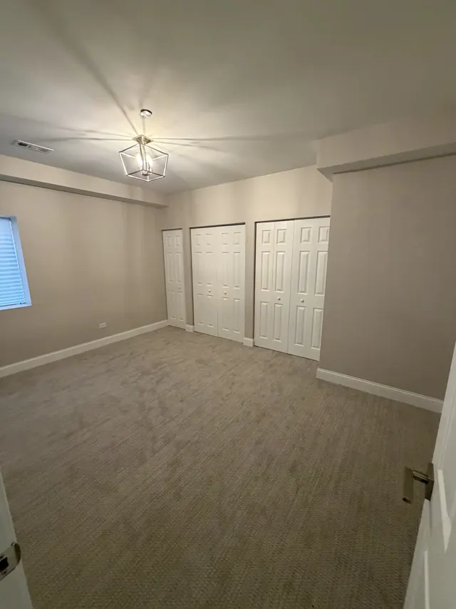 Carpeted bedroom with two double closets and a modern pendant light