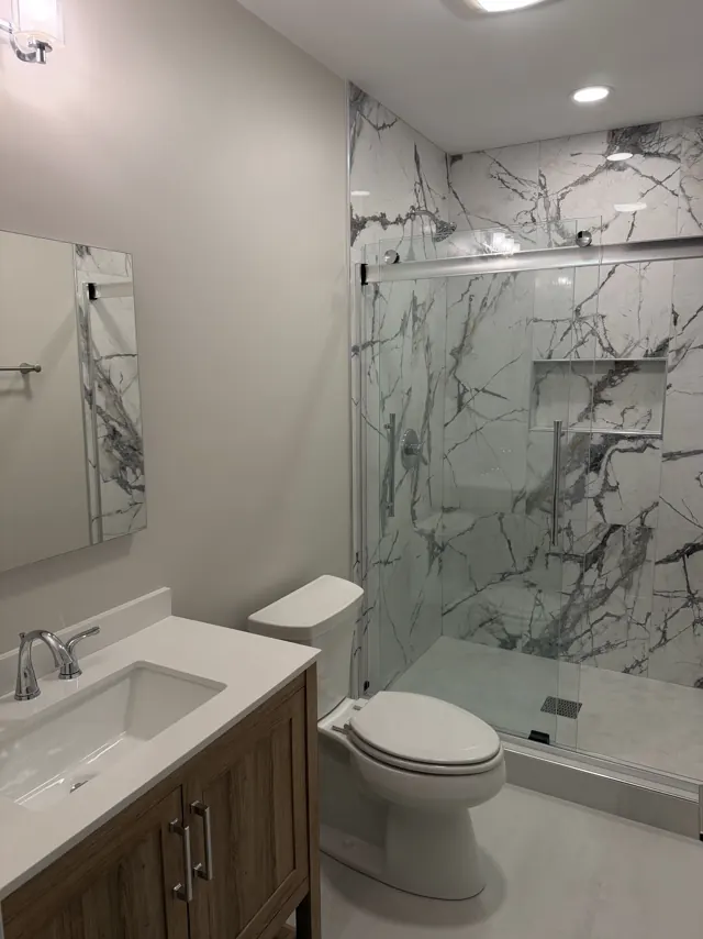 SRC bathroom with a marble-look walk-in shower, sliding glass door and wood vanity